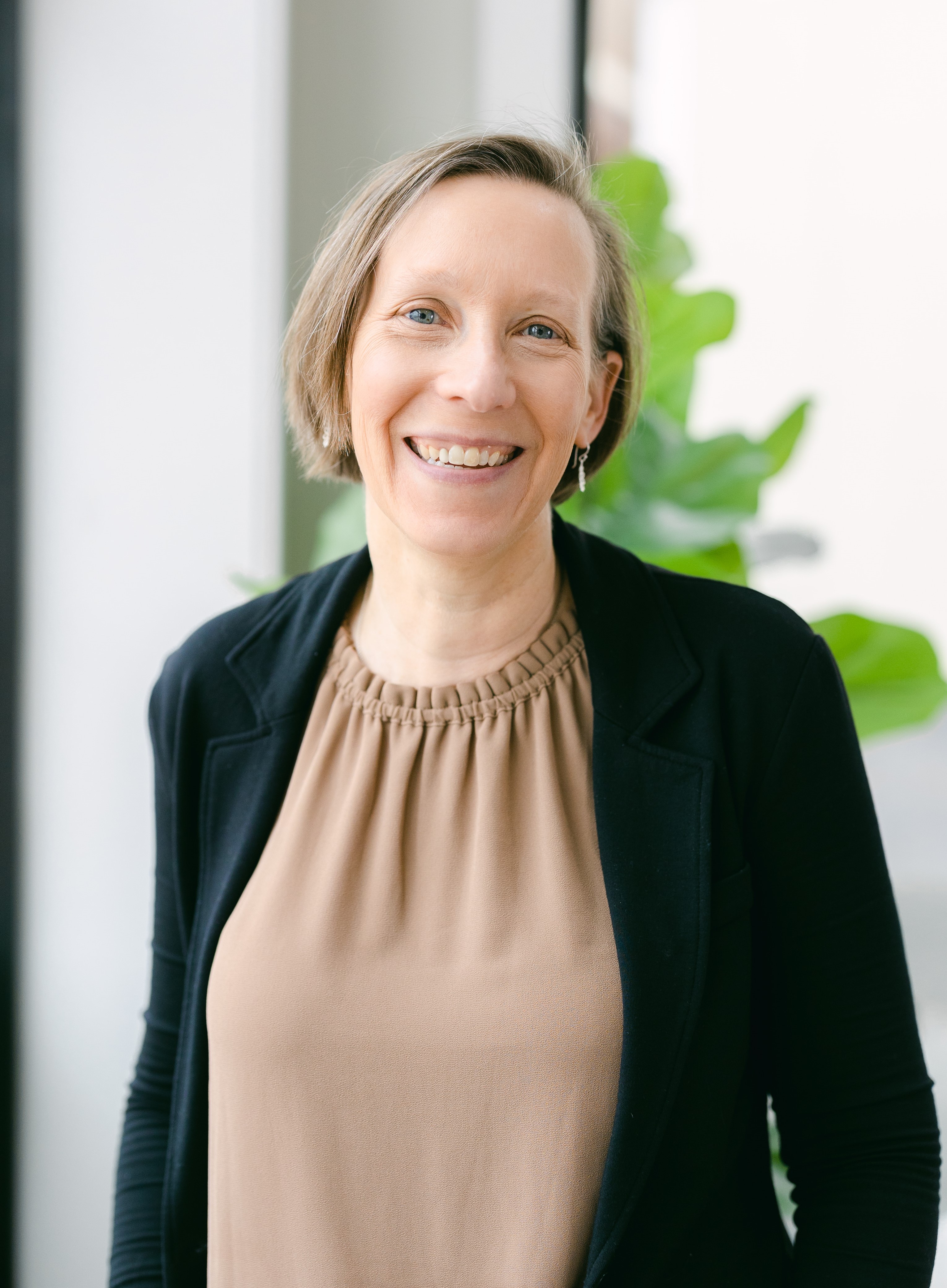 A woman with short hair smiles joyfully.
