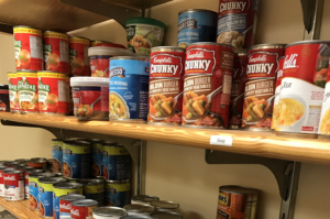Shelves stocked with various canned goods, including cans of soup, tomatoes, and vegetables. The products are arranged neatly, showcasing different brands and labels.