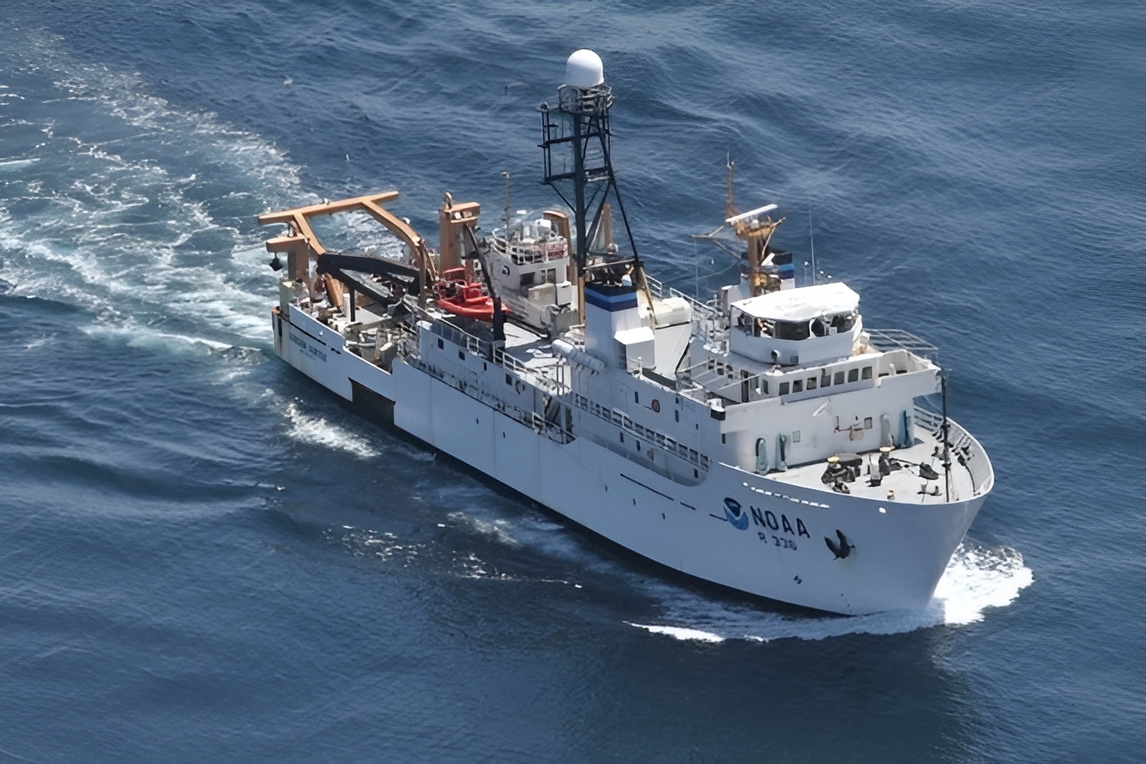 A white NOAA research vessel travels through the ocean, equipped with scientific instruments and equipment on its deck.