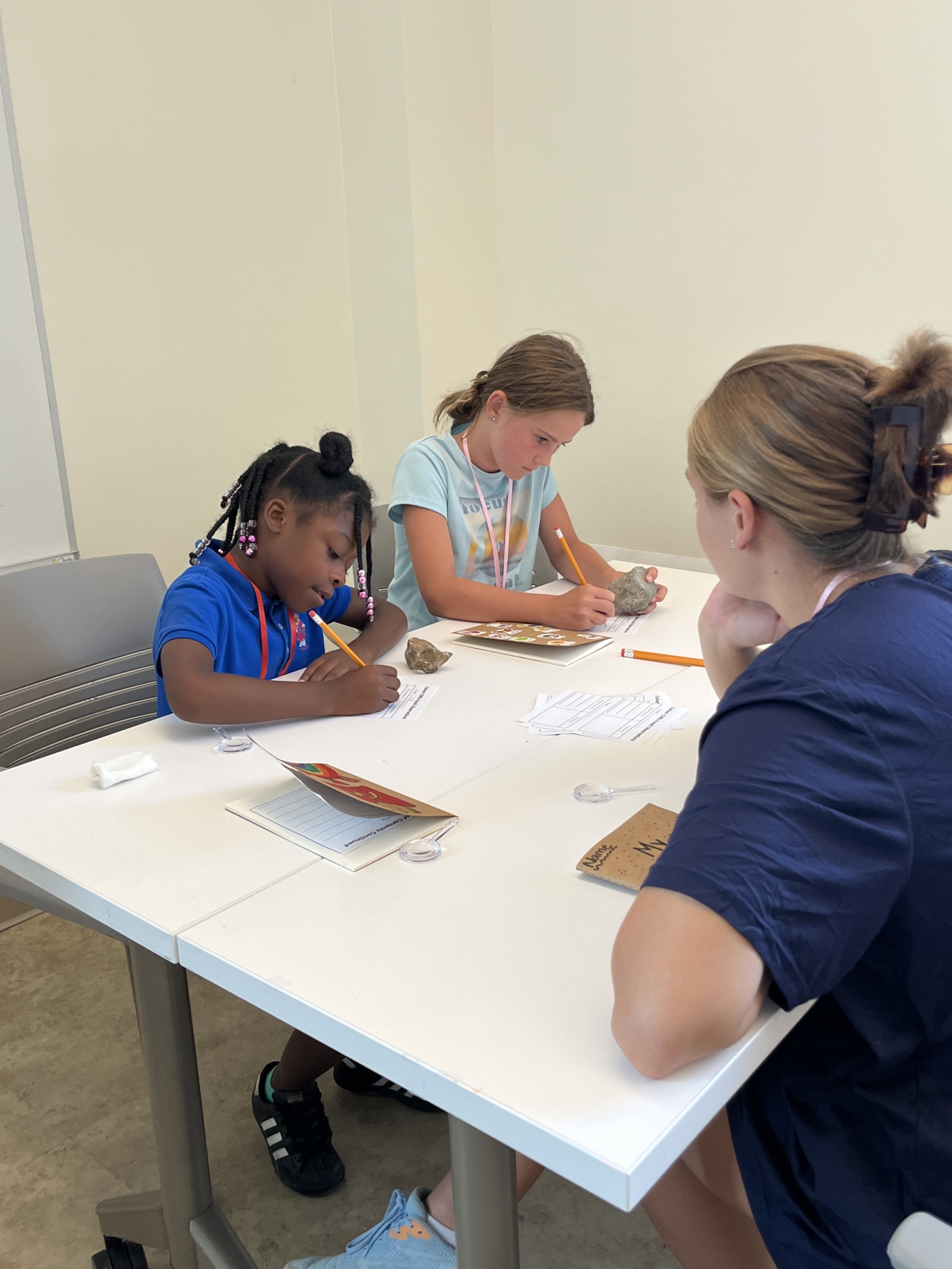 Student teacher helping two young girls with their writing.