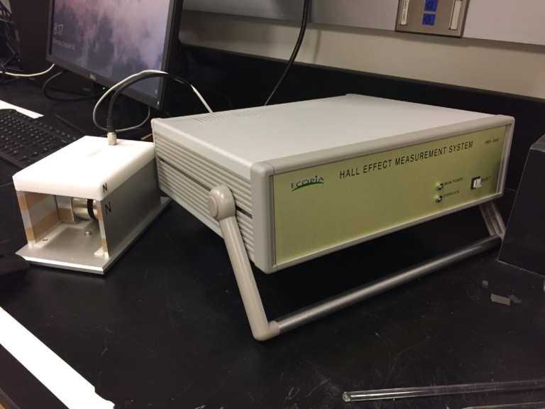 A Hall effect measurement system with a control unit and a sample holder placed on a laboratory bench.