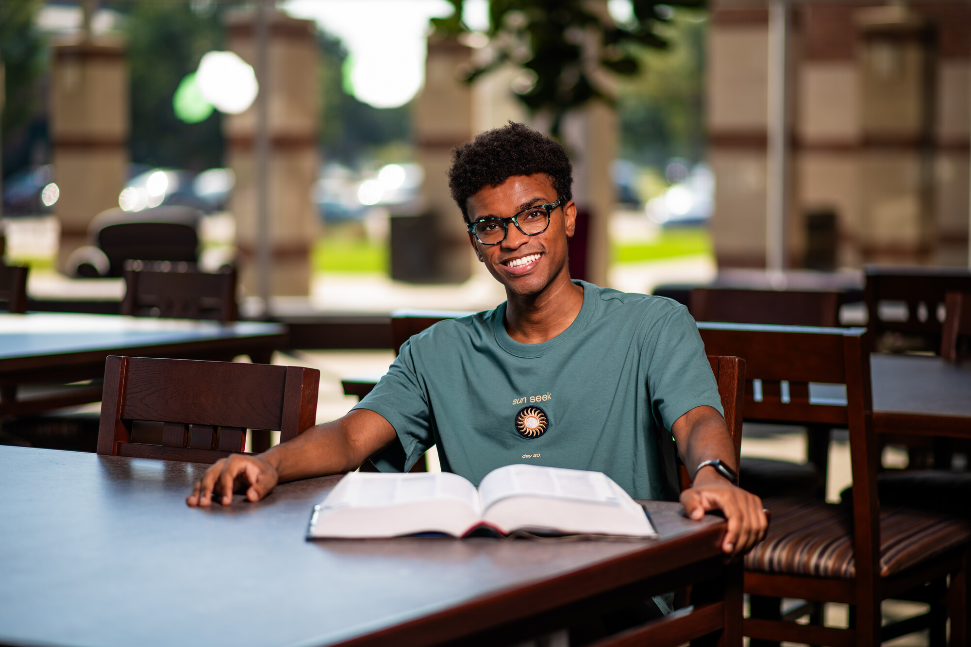 male student at desk with open book 