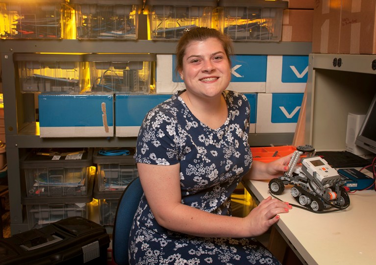 Samantha Smith smiles at the camera while sitting at a desk.