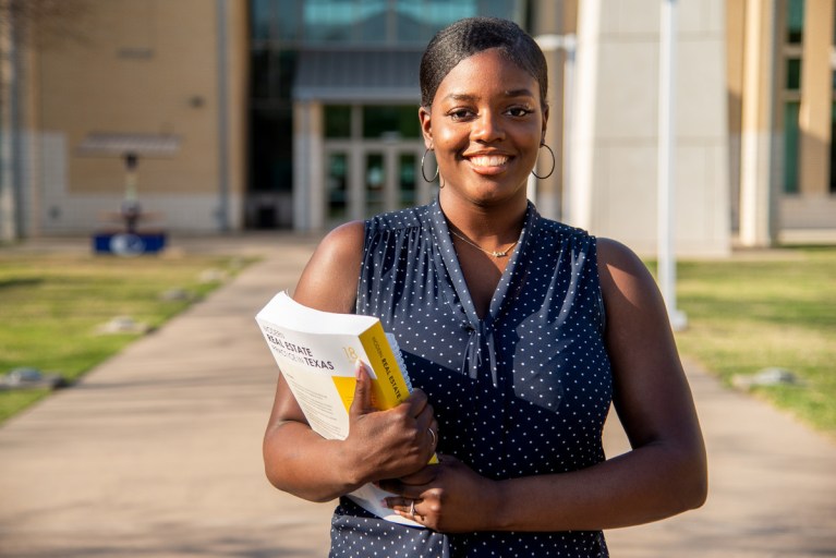 Image of Hadassah Black outside of a Collin College building smiling and holding a textbook.